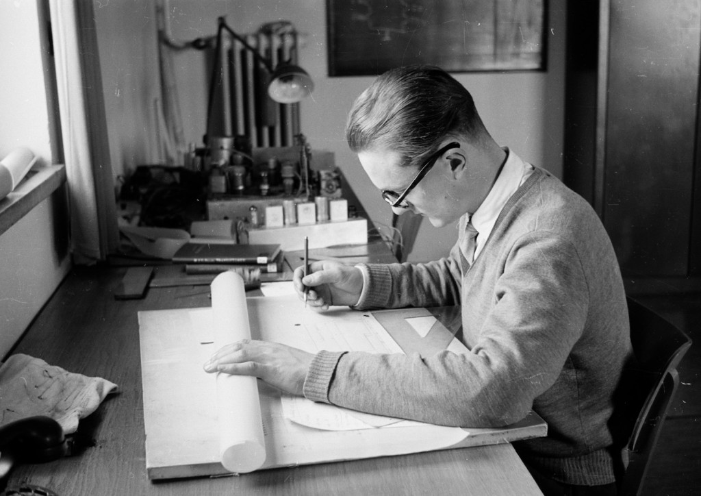 Nuori mies työpöydän ääressä kopioi piirustuksia.